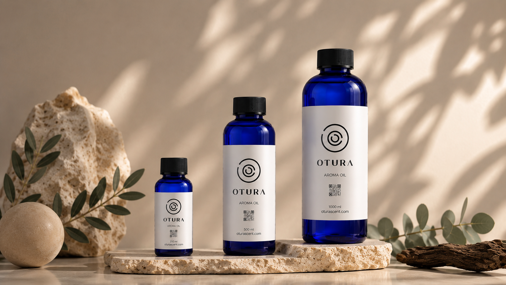 Otura luxury aroma oil bottles in 250ml, 500ml and 1000ml sizes displayed on a natural stone surface with eucalyptus leaves – premium cold-air diffuser oils UAE
