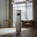 Otura Essence Modern air purifier in a living room setting with large windows and a brown leather sofa.